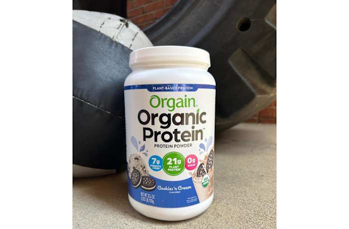 A tub of Orgain organic protein powder in Cookies 'n Cream flavor  on the floor of a Crossfit gym